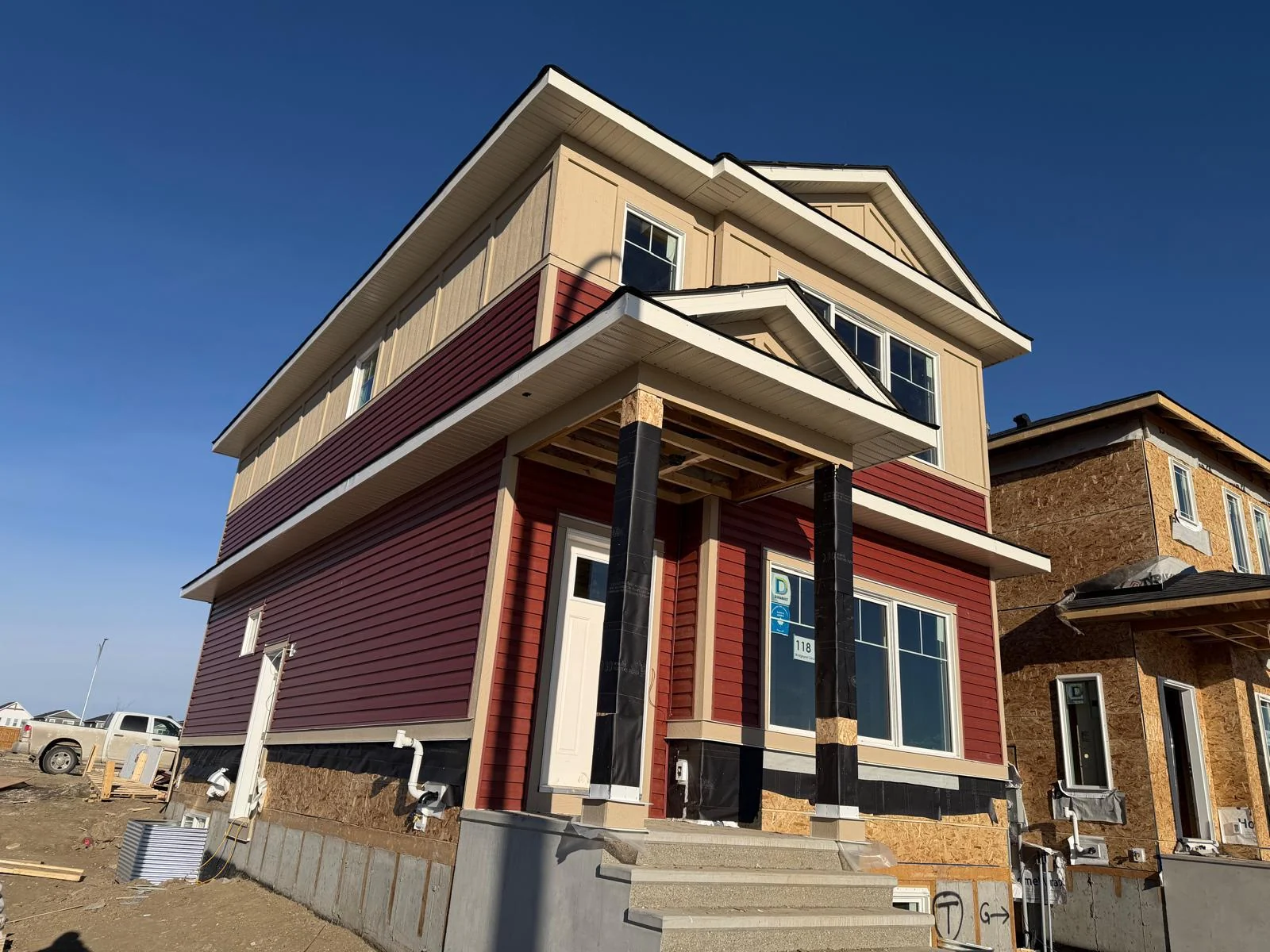 Red horizontal siding and light upper facade during construction