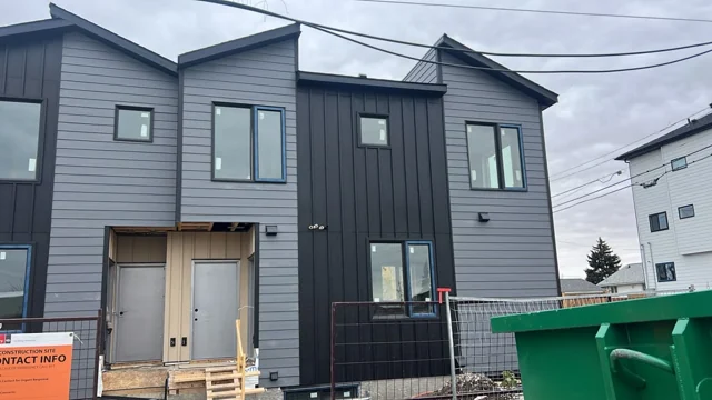 Grey horizontal siding and dark vertical panels during construction